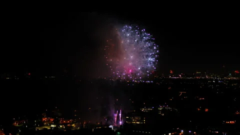 Aerial Panning Shot Of Fireworks Exploding In Neighborhood Against Sky, Drone Stock Footage 243883342