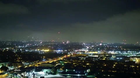 Aerial Panning Shot Of Fireworks Exploring Over Houses In City At Night - Los Stock Footage 264046487