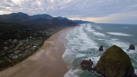 Aerial Panning Shot Of Haystack Rock In Sea By Residential Coastal City Under Video stock 260469856