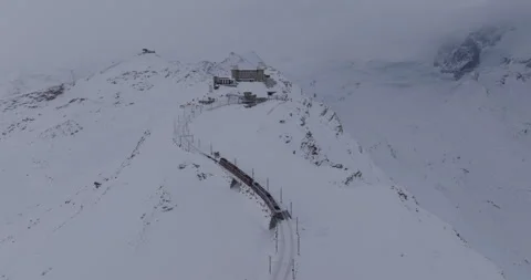 Aerial Panning Shot Of Train Moving On Snowcapped Mountain With Observatory Stock Footage 309329681