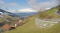 Aerial panorama of Alpine village on green mountain hills, cloudy sky, tourism 4k or 4k+ Resolution