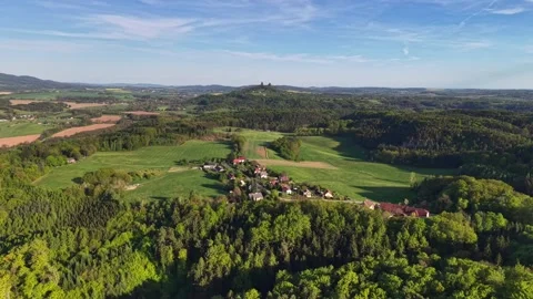 Aerial panorama over patchwork fields and village cluster beneath blue sky, Stock Footage 346262940