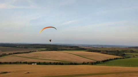 Aerial panorama of paragliding pilot with paramotor flying midair above 库存影片 334684040