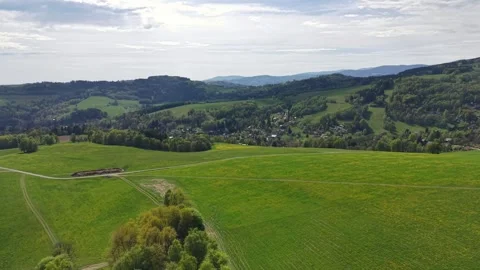 Aerial panorama of rolling patchwork hills with scattered village and winding Stock Footage 346262976