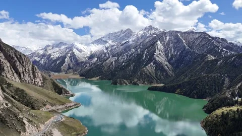 Aerial panorama of snow mountain lake and forested valley in Xinjiang China Stock Footage 337887053