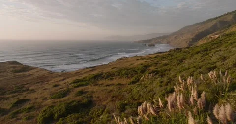 Aerial panoramic pullback of Highway 1, waves crashing below rocky cliffs Stock-Footage 295265428