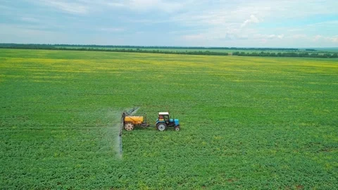 Aerial panoramic side view of a tractor machine spraying the field with Stock Footage 197059159