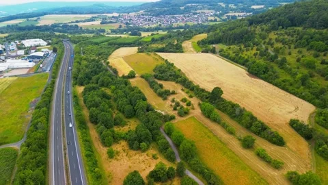 Aerial panoramic view of highway passing through rolling farmland, forest, and Stock Footage 340403844