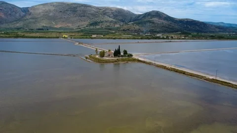 Aerial panoramic view of isolated chapel beside lagoon, mountain and salt flats Stock Footage 337048749