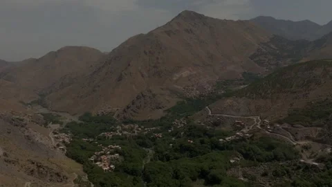 Aerial panoramic view of a lush green river oasis and Berber village snaking Stock Footage 345731015
