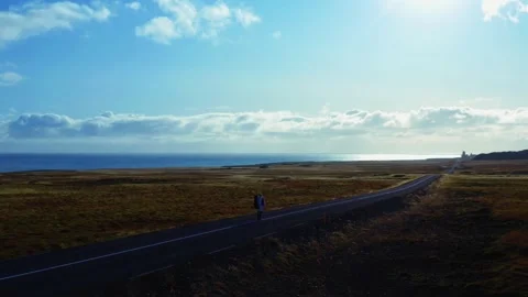 Aerial panoramic view of man walking center line of road to mountain range Stock Footage 168078858