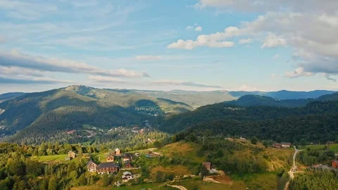 Aerial panoramic view of mountain range, road, and fir forest with village Stock Footage 121311522