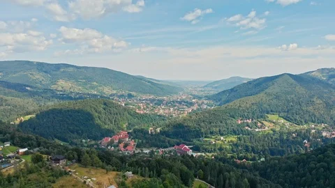 Aerial panoramic view of mountain range, road, and fir forest with village Stock Footage 121904805