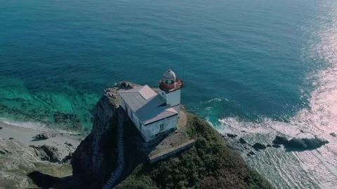 Aerial panoramic view of white lighthouse on the rocky cliff at seaside. Waves Video stock 167718340