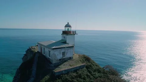 Aerial panoramic view of white lighthouse on the rocky cliff at seaside. Waves Video stock 167718534