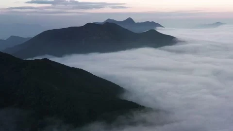 Aerial parallax of dense layer of clouds passing between mountain tops at Stock Footage 171335827
