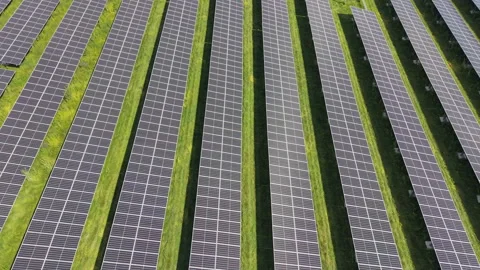 Aerial Pattern of Converging Solar Panel Rows and Green Grass Aisles Stock Footage 345716275