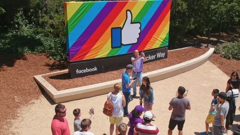 Aerial: People posing in front of the facebook logo at Facebook headquarters, Stock Footage 77405086