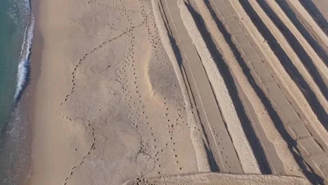 Aerial perspective of beach with waves and lounge chair patterns Stock-Footage 332129235