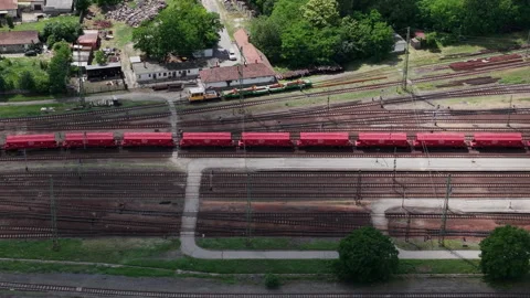 An aerial perspective captures a long red cargo train moving through a rural Stock Footage 337471542