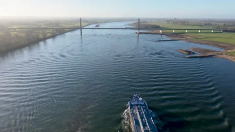 Aerial perspective of a cargo vessel sailing towards a modern cable stayed Stockbeeldmateriaal 331281348
