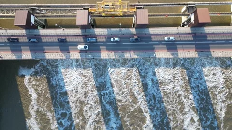 Aerial perspective of a dam on a river, featuring flowing water and vehicles Stock Footage 325377790