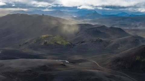 Aerial perspective of dark lava fields with moss-covered cinder cones, braide Stock Photos