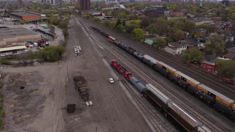 Aerial perspective of freight train travelling on rail tracks through urban area Stock Footage 334697186
