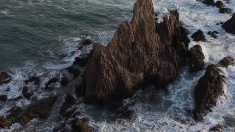 Aerial perspective of powerful ocean waves crashing against the rugged rocks Stock Footage 333897286