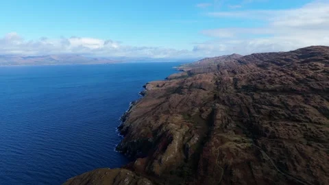 An aerial perspective reveals the dramatic, rocky coastline. Blue skies Stock Footage 312990884
