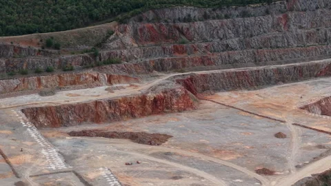 An aerial perspective shows a large open pit quarry with exposed rock strata Stock Footage 340896562