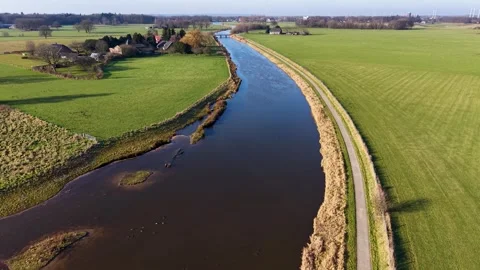Aerial perspective of a winding river cutting through vibrant green Dutch Stock-Footage 329450211
