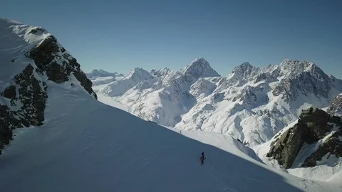 Aerial of pro freeriders standing on top of snowy hill with mountain landscape Stock Footage 121580433