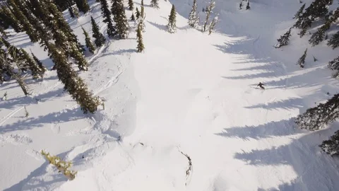 Aerial of pro skier skiing down fast on snowy hill on sunny day, Red Mountain Stock Footage 121586677