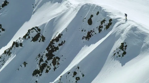 Aerial of pro skier skiing down from snowy ridge on rocky terrain in Iceland Stock Footage 124227083
