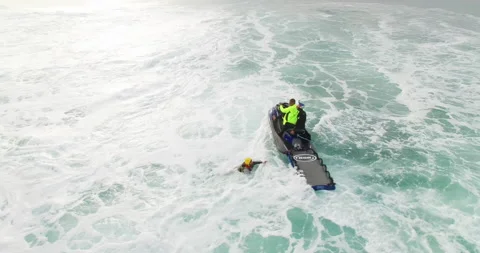 Aerial of pro surfer getting on rescue sled and being pulled out of ocean Stock Footage 160499565