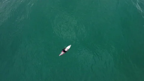 Aerial of professional surfer sitting down on surfing board in middle of ocean Stock Footage 157157684
