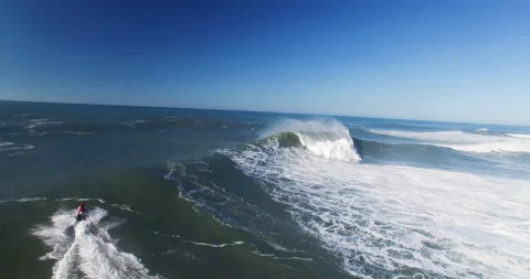 Aerial of professional surfer using jet ski to carry fellow surfer across ocean Stock Footage 155796170