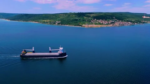 Aerial profile of cargo ship sailing near green hills Stock Footage 335319286