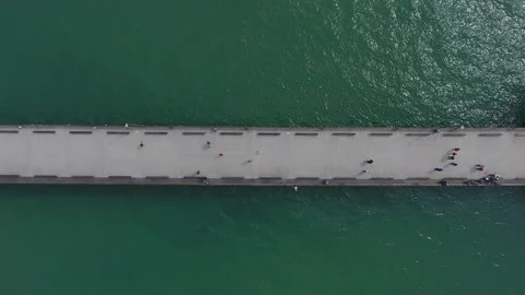 Aerial pull away of long pier running through glistening green water Stock Footage 157137954