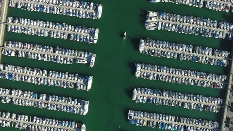 Aerial pull away over Dana point harbor with boat riding through teal water Stock Footage 157175048