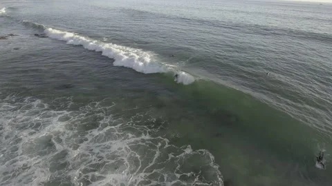 Aerial pull away over two surfers riding a wave in the summer Stock Footage 157133520