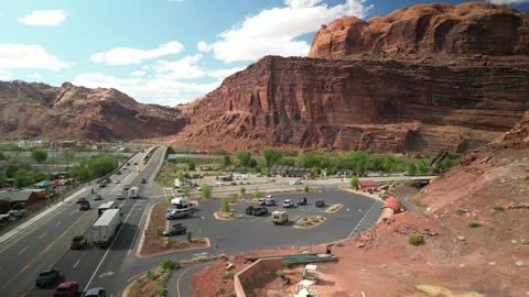 Aerial pull away from parking lots on highway 191 through Moab Utah 스톡 동영상 240858135