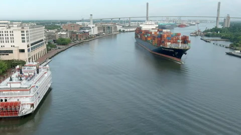 Aerial pull away shot of cargo ship passing through Savannah, Georgia Stock Footage 154877825