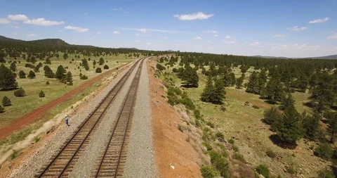 Aerial pull away from a single man standing along the parallel train Video stock 113444287