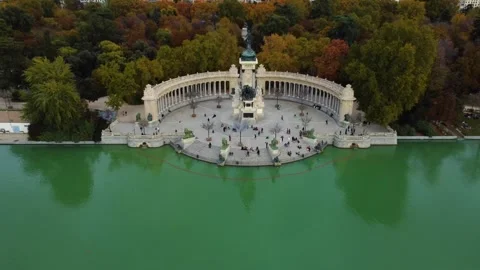 Aerial pull back from Alfonso XII Monument in El Retiro Park during autumn Stock Footage 328385019