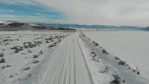 Aerial-Pull back and descend over snowy road to distant mountain valley Stock Footage 101450978
