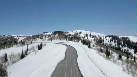 Aerial-Pull back-Ascend-snow lined road on mountain top Stock Footage 243848274