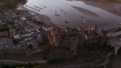 Aerial pull back Conwy Castle, Wales, with river and Irish sea behind, summer Stock Footage 204923328