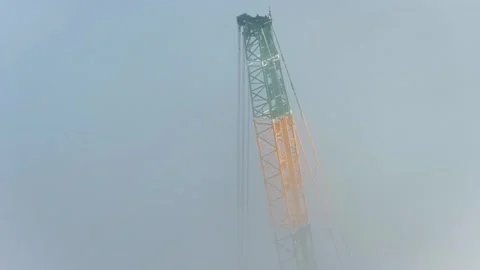 Aerial Pull Back of Crane Building Wind Turbine in Clouds at Latvian Wind Farm Video stock 315260411